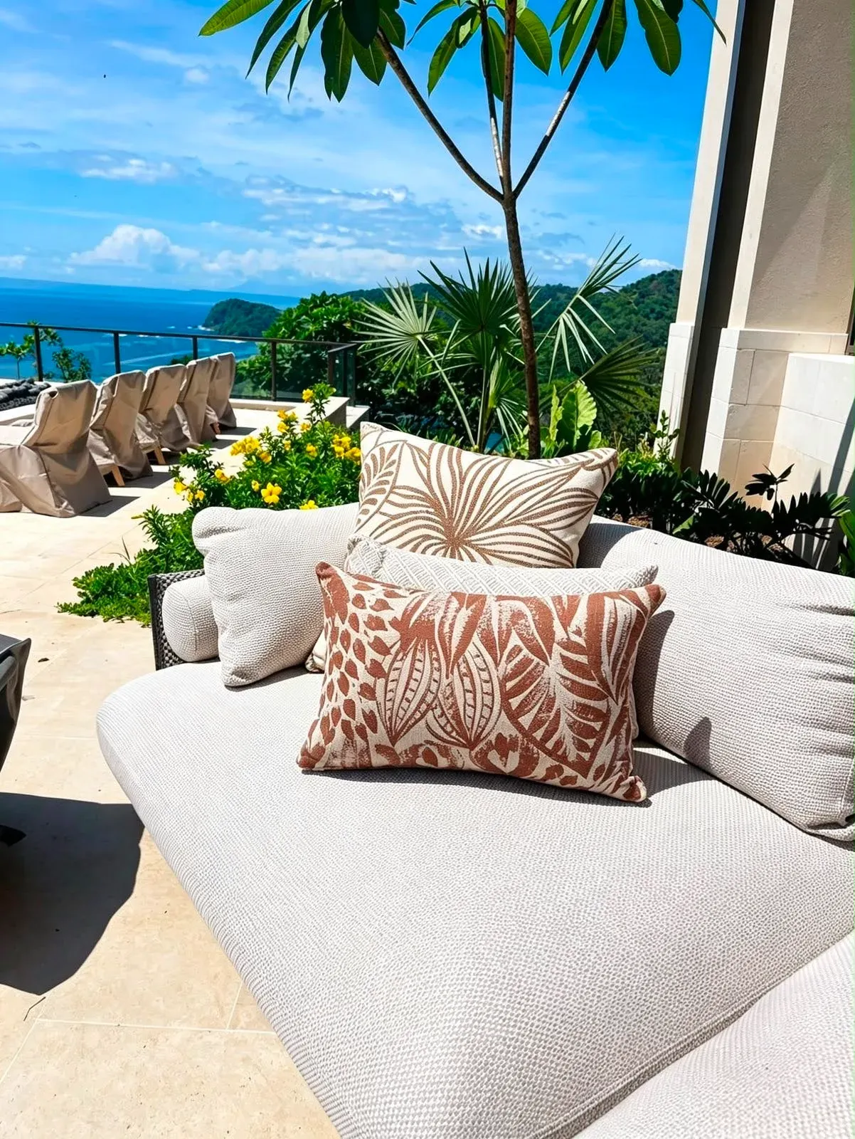Cojines estampados sobre sofá en terraza con vista al mar.