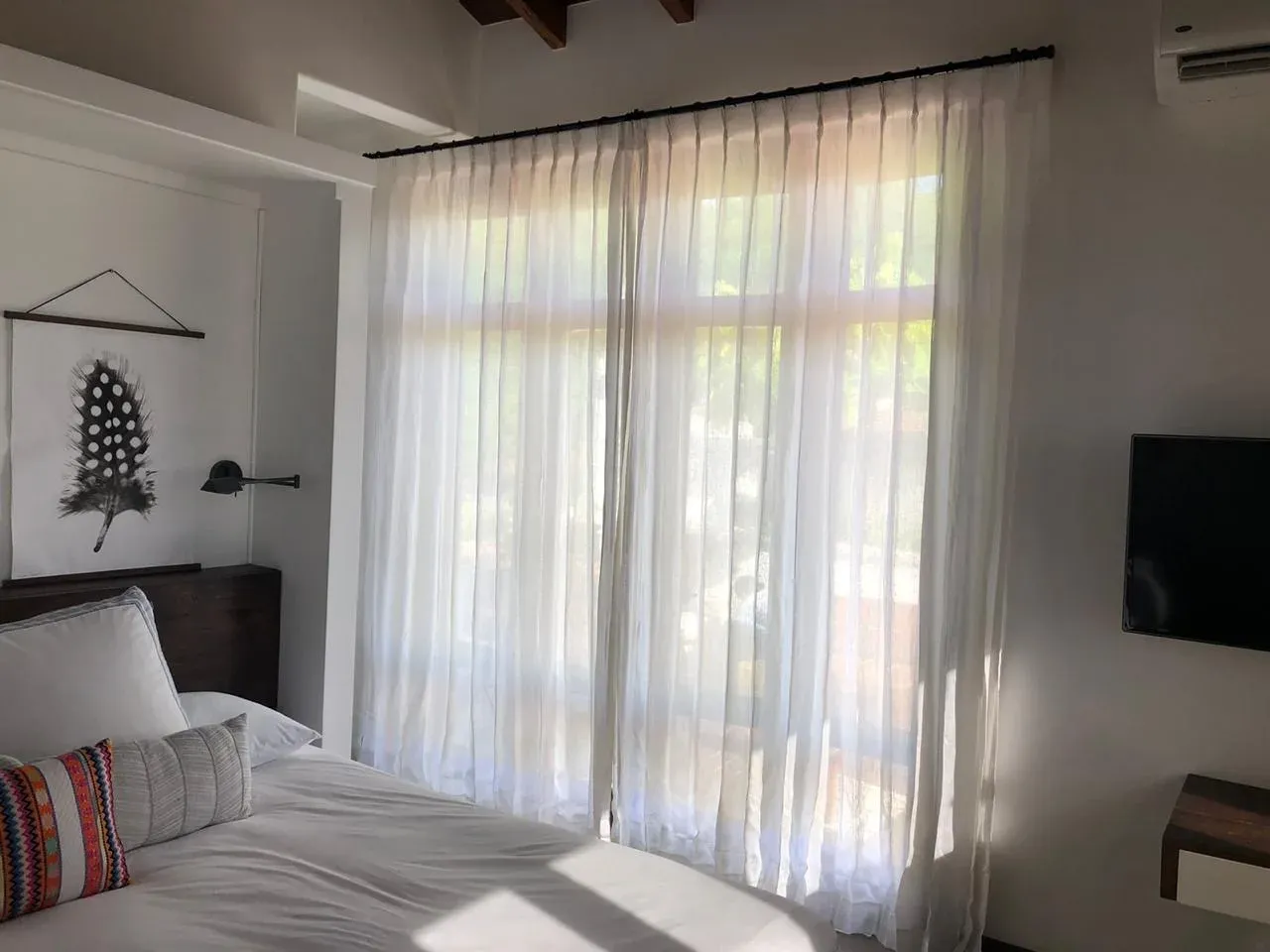 Cortinas de tela en dormitorio con agarra-cortinas de madera.