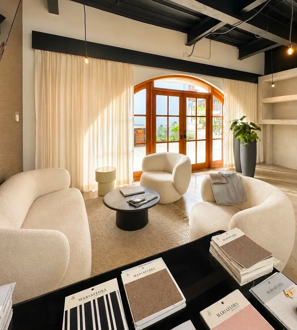 Sala con cortinas vaporosas y muestrarios de tela abiertos sobre la mesa de centro.