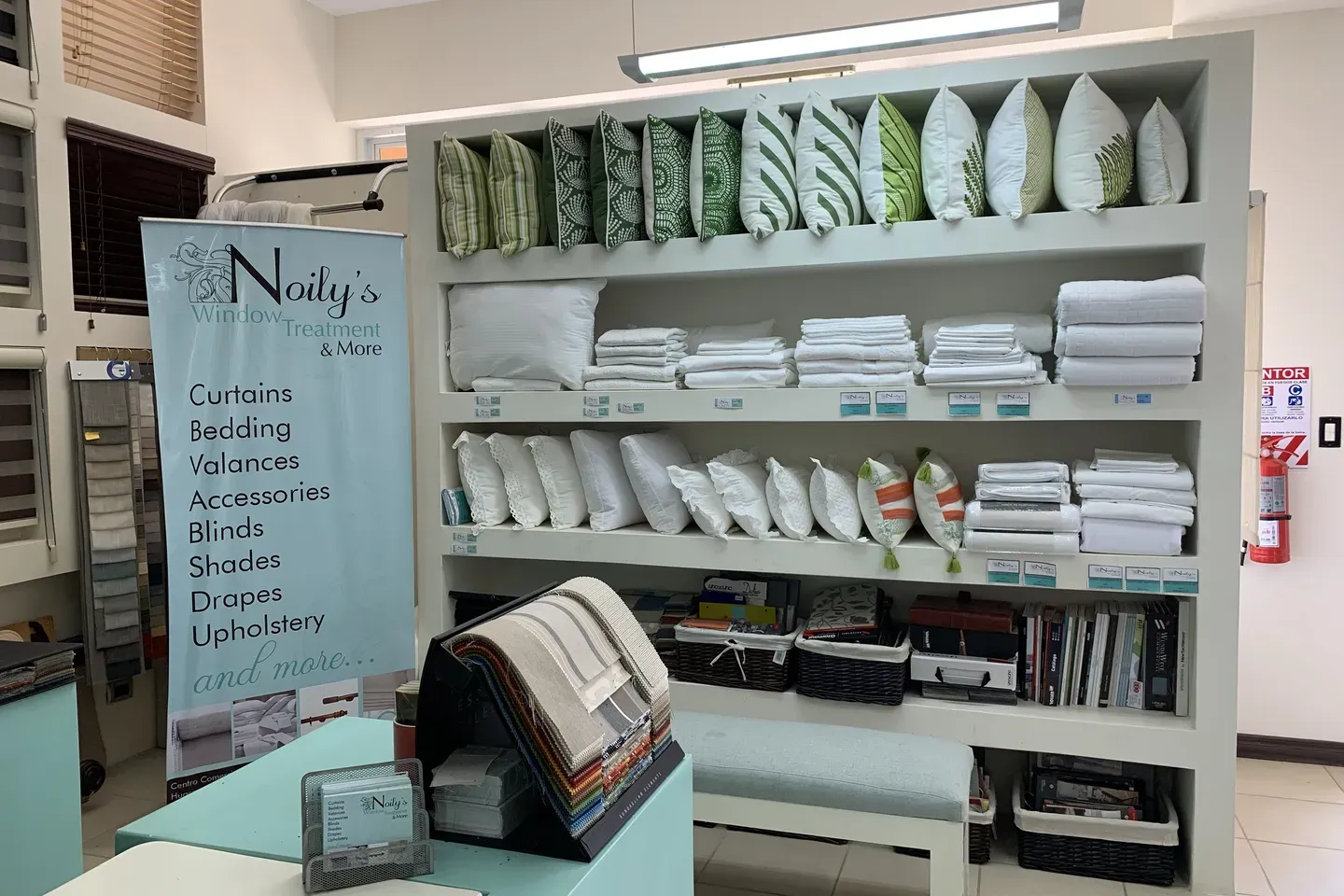 Interior del showroom de Noily's Window Treatment con muestrarios y cojines