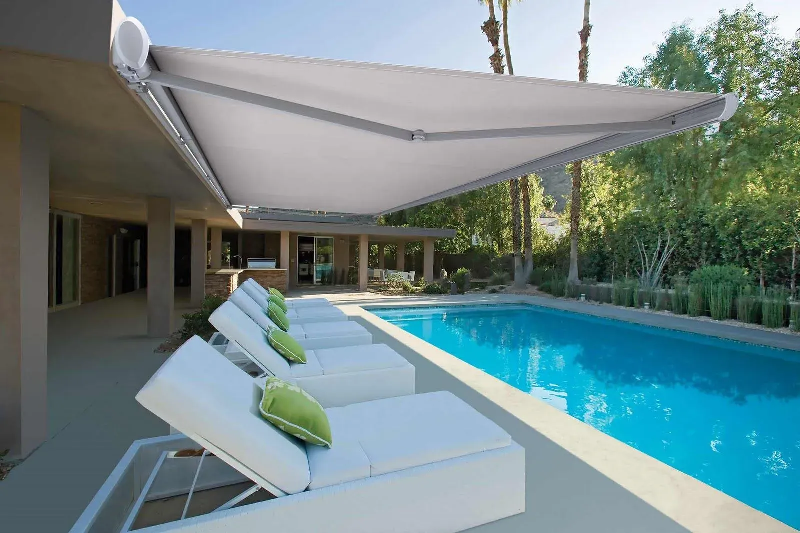 Toldo retráctil instalado en terraza amplia con vista al jardín.